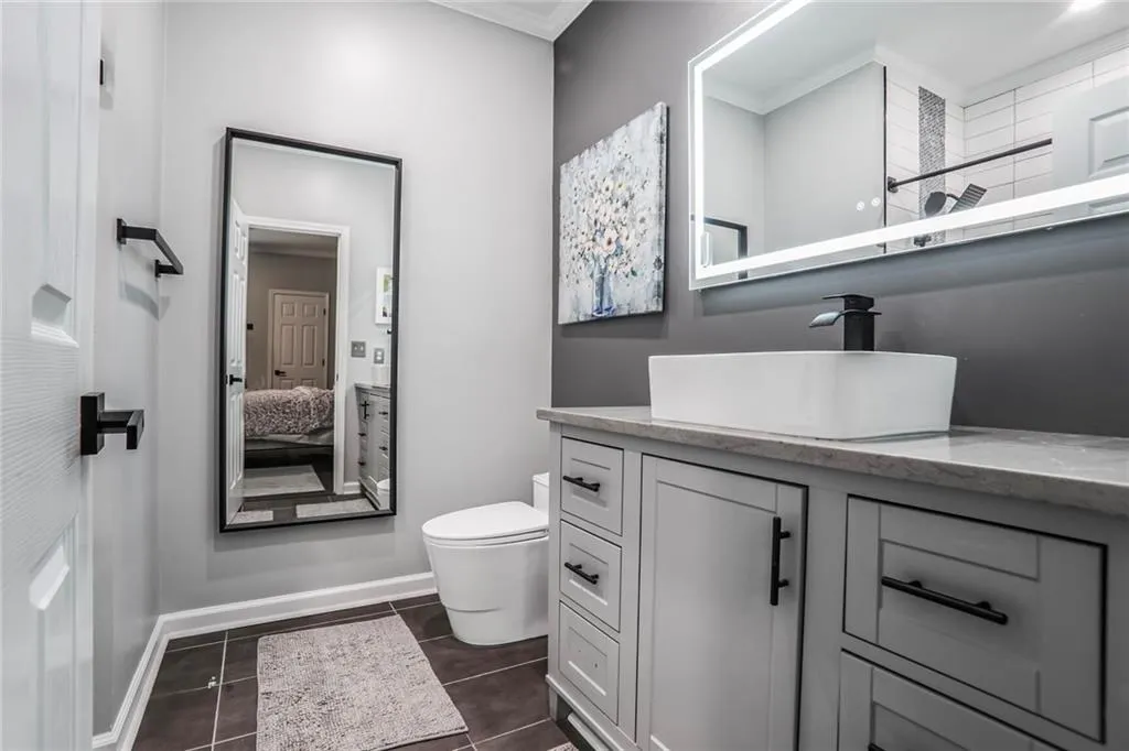 Full bathroom featuring vanity, toilet, ornamental molding, tile patterned flooring, and baseboards