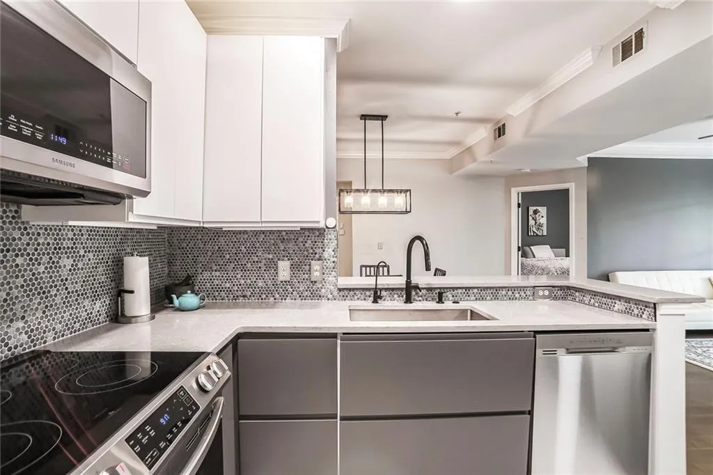 Kitchen with appliances with stainless steel finishes, a sink, gray cabinets, crown molding, and decorative backsplash