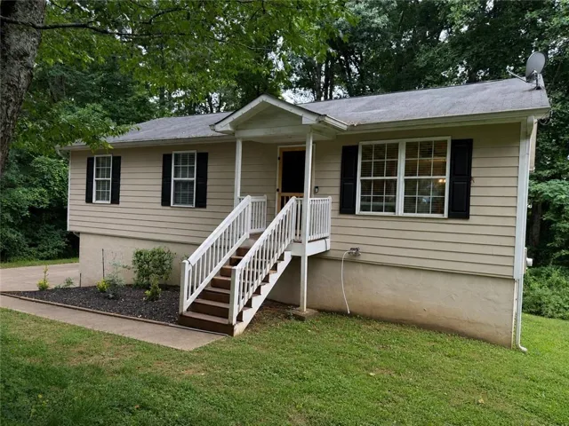 Ranch-style exterior featuring beige siding, black window shutters, and a covered front porch with white railings