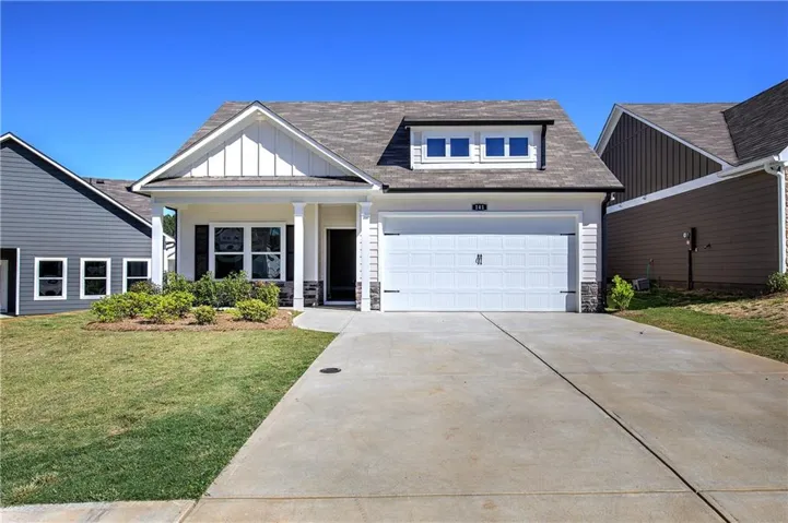 Contemporary home with a two-car garage, dormer window, and an inviting front porch