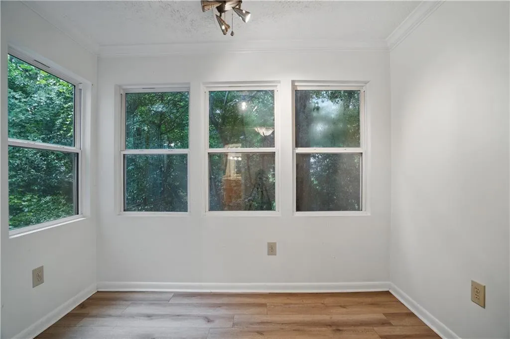 Unfurnished room with wood finished floors, crown molding, and baseboards
