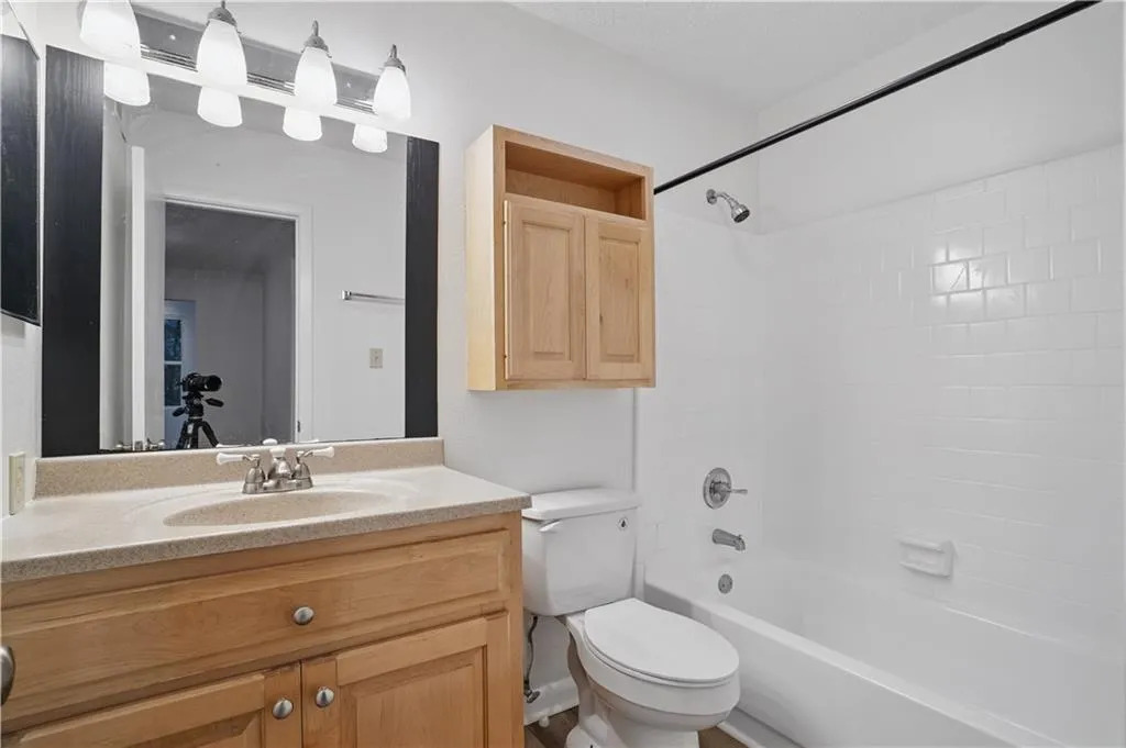 Bathroom with toilet, vanity, and washtub / shower combination