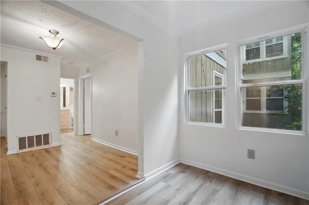 Empty room with light wood-type flooring, crown molding, and baseboards