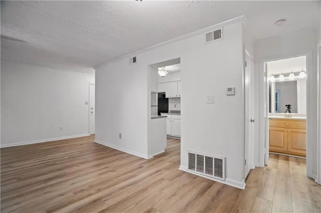 Spare room with light wood finished floors, a textured ceiling, and baseboards