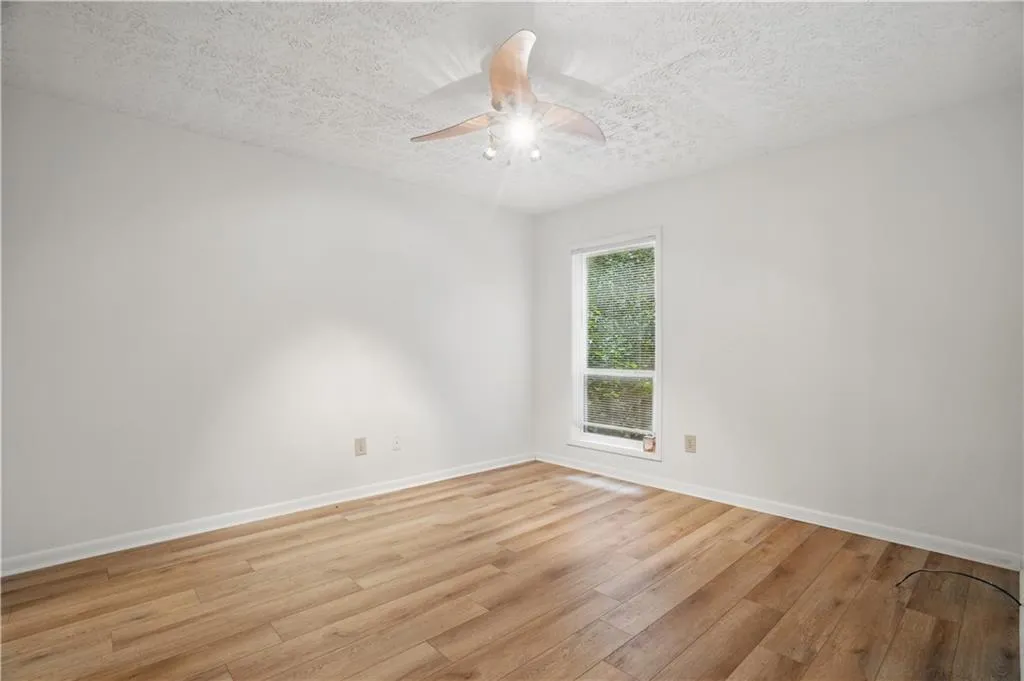 Unfurnished room featuring light wood finished floors, a textured ceiling, baseboards, and a ceiling fan