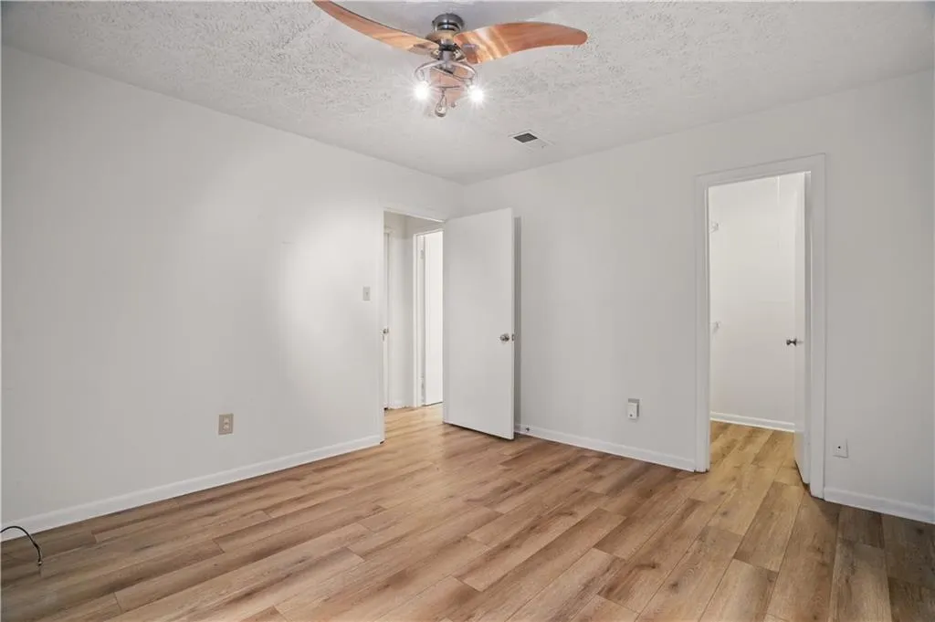 Unfurnished bedroom with light wood finished floors, a textured ceiling, baseboards, and ceiling fan