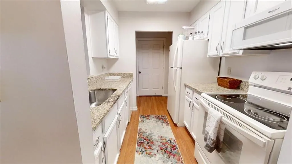 Kitchen featuring electric stove, white cabinetry, ventilation hood, light stone counters, and light wood-style flooring