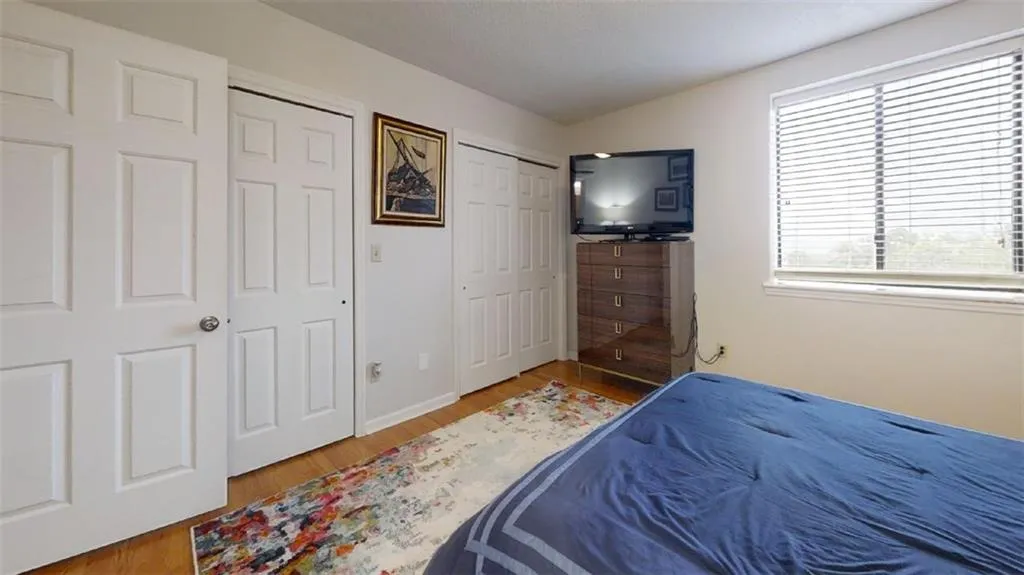 Bedroom with light wood-type flooring, vaulted ceiling, and a closet