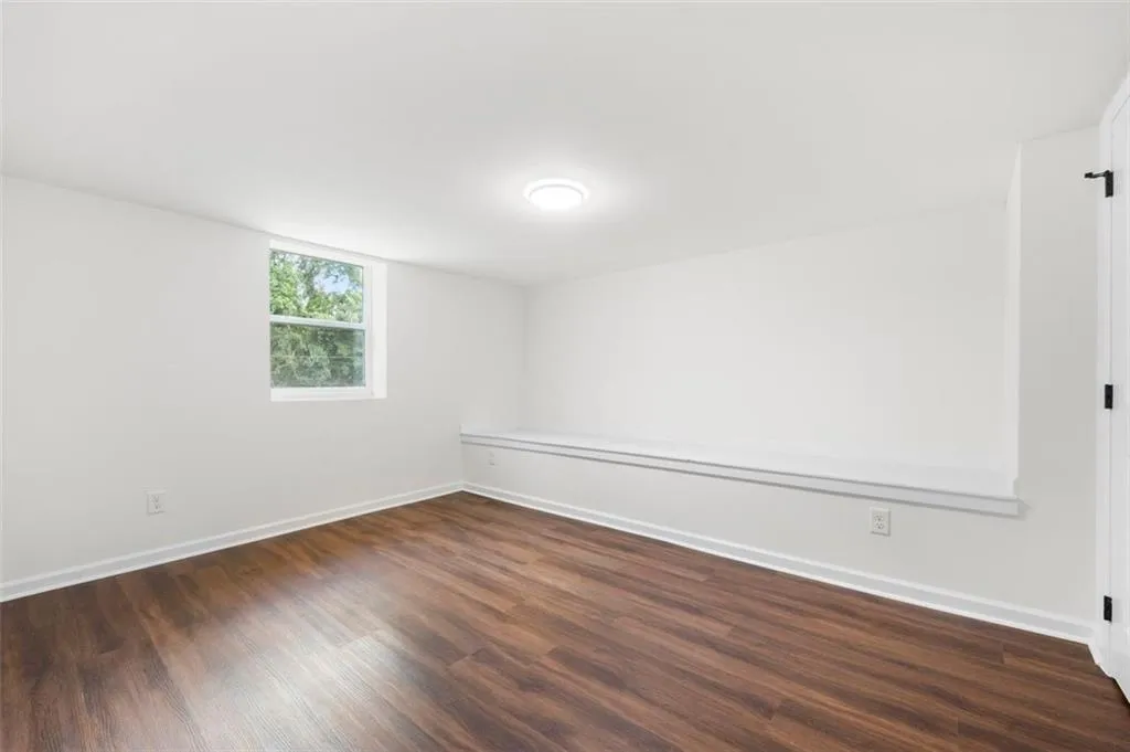 Spare room featuring baseboards and dark wood-type flooring