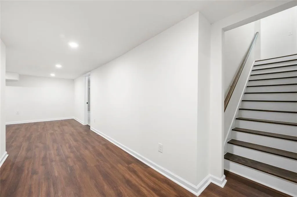 Below grade area with dark wood-type flooring, stairs, and recessed lighting