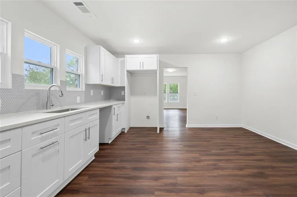 Kitchen featuring white cabinets, dark wood-style flooring, decorative backsplash, recessed lighting, and light stone countertops