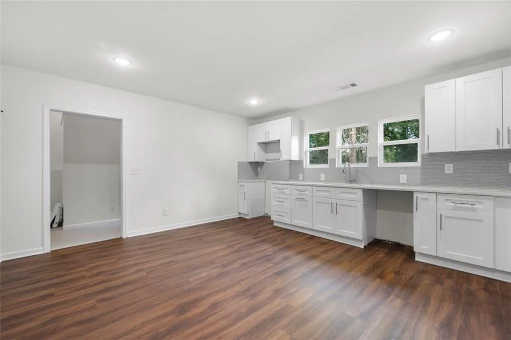 Kitchen with white cabinetry, decorative backsplash, dark wood finished floors, and recessed lighting