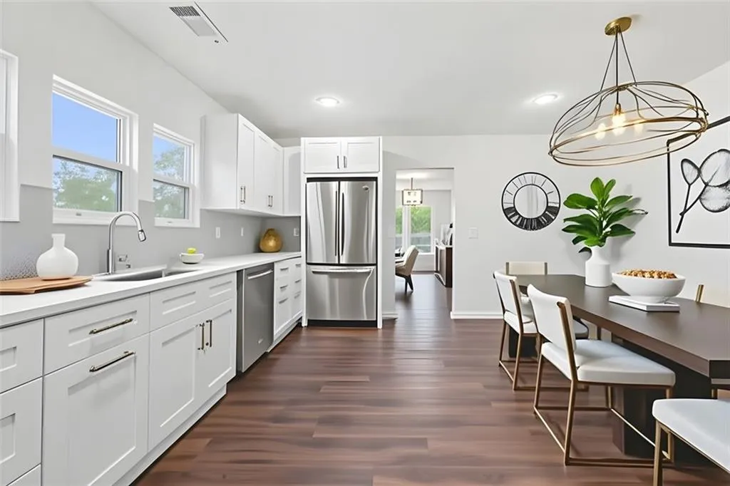 Kitchen with stainless steel appliances, white cabinets, dark wood finished floors, hanging light fixtures, and recessed lighting