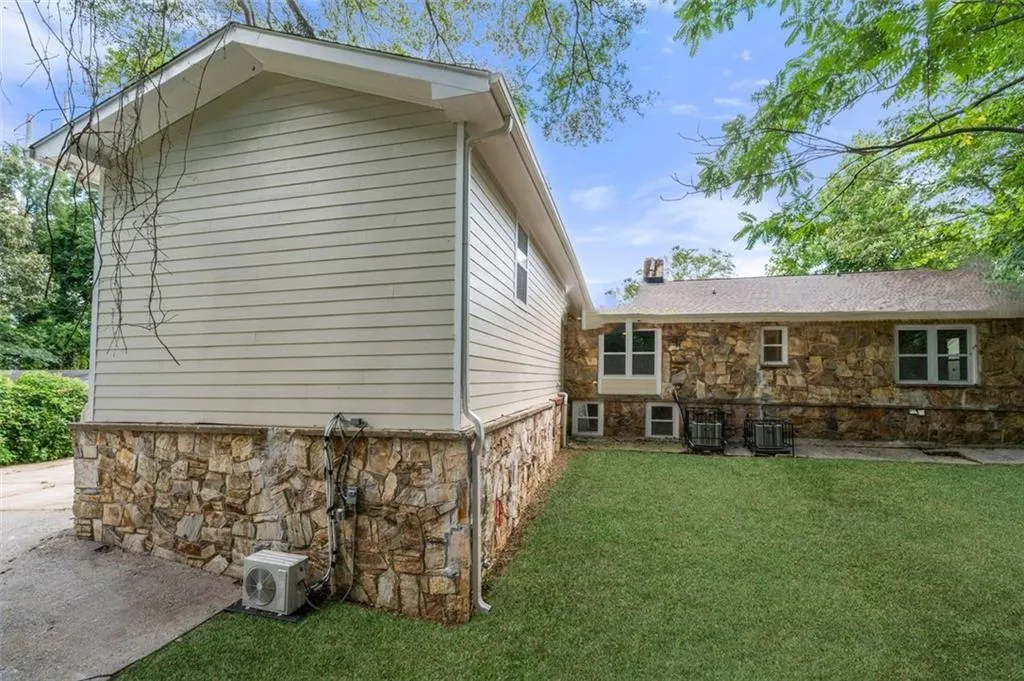 View of side of property with stone siding and a lawn