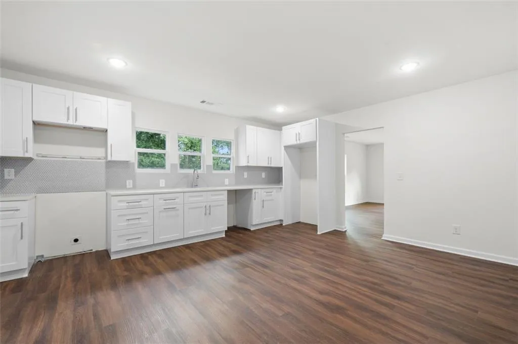 Kitchen with tasteful backsplash, white cabinetry, dark wood finished floors, and recessed lighting