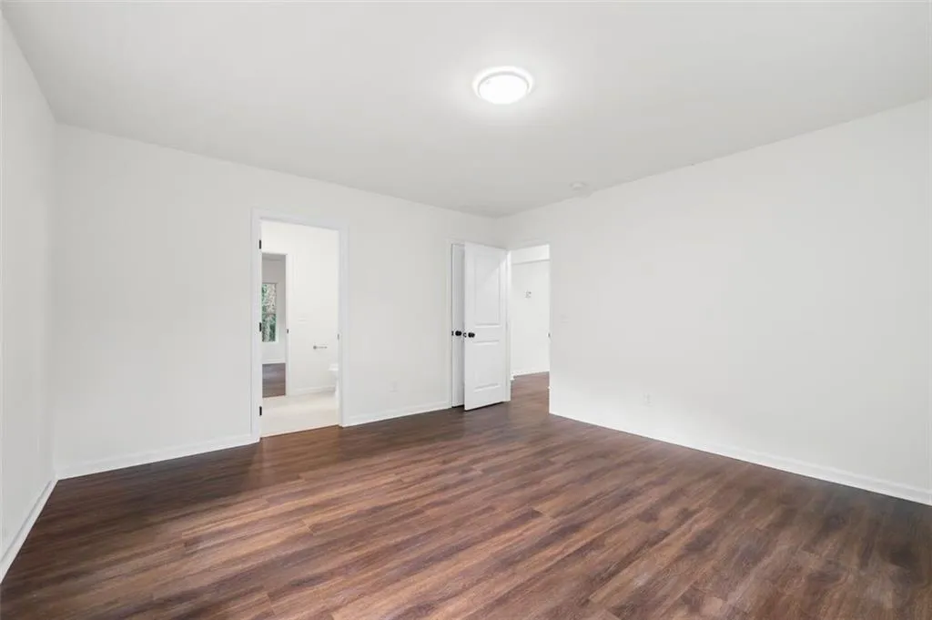 Unfurnished bedroom with dark wood-type flooring and connected bathroom