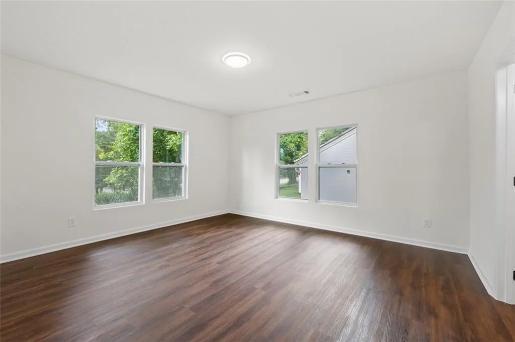 Spare room with dark wood-type flooring and baseboards