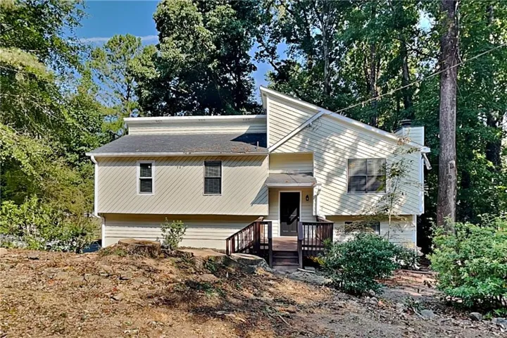 Light-colored exterior siding with contrasting dark trim windows, front entry with covered porch, and wood-finish railings