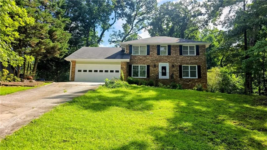 Two-story brick exterior with black shutters, a two-car garage, and a concrete driveway