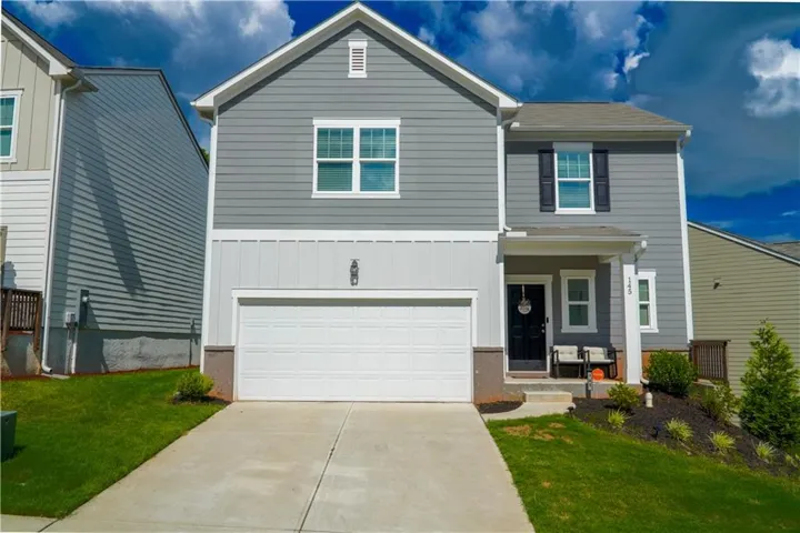 Modern two-story residence featuring grey siding with white trim, an attached front-entry garage, a concrete driveway, and a covered entryway