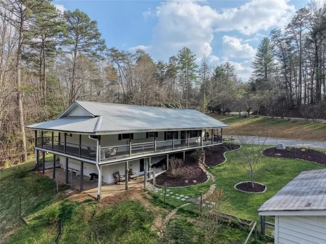 Back of property with a lawn, a metal roof, and covered porch