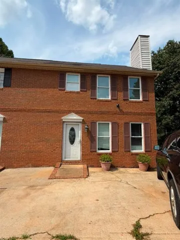 Brick exterior with white entry door featuring an oval glass insert and a decorative pediment