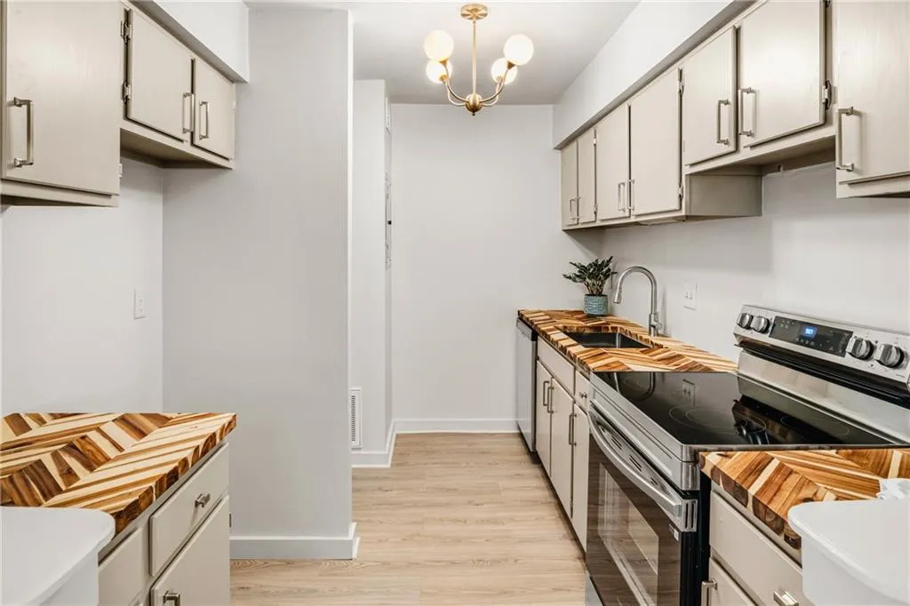 Kitchen featuring stainless steel appliances, wood counters, light wood-type flooring, hanging lights, and gray cabinetry