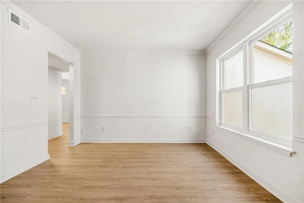 Empty room featuring light wood-style flooring and ornamental molding