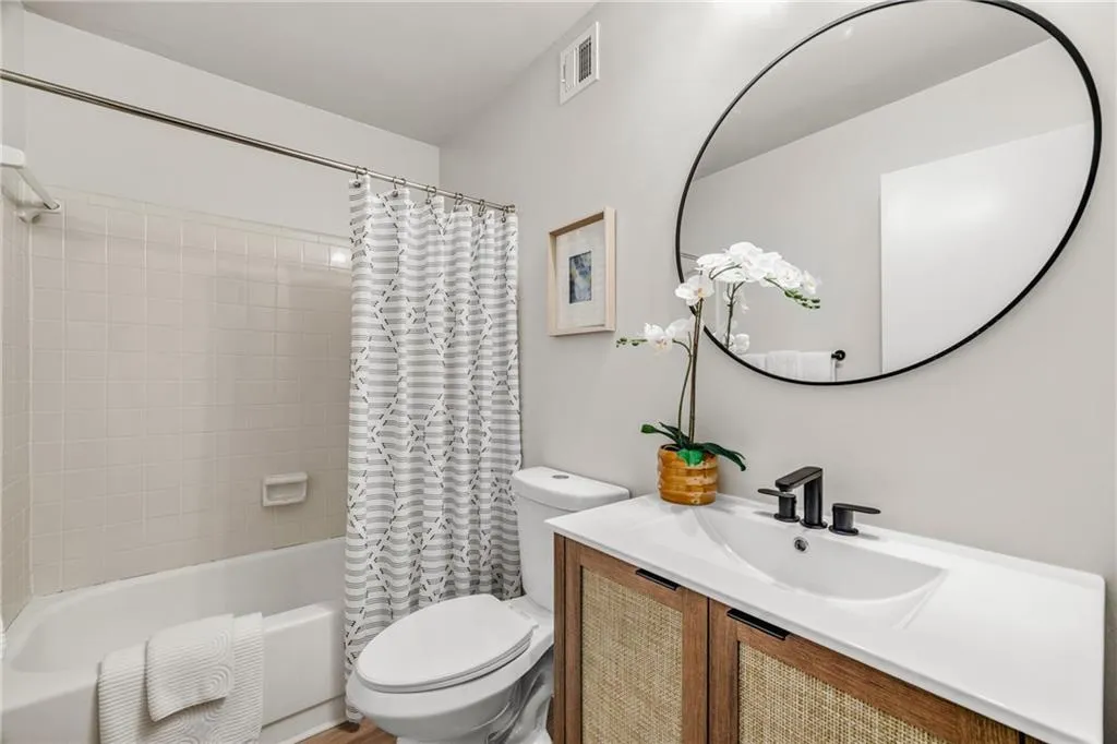 Bathroom featuring vanity and shower / bathtub combination with curtain