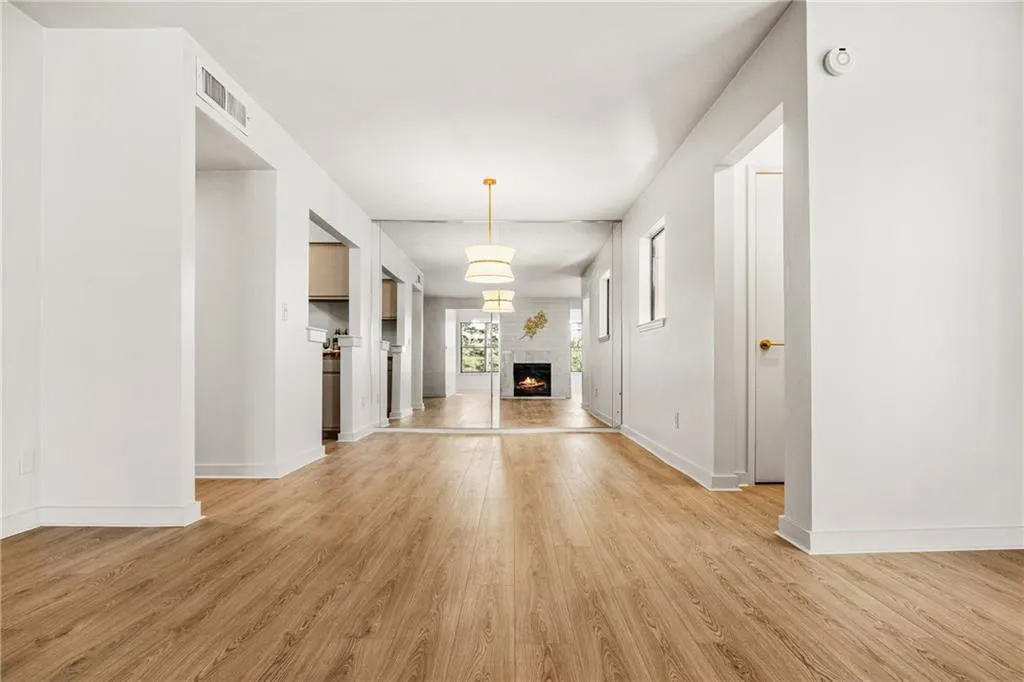Unfurnished living room with a warm lit fireplace and light wood finished floors