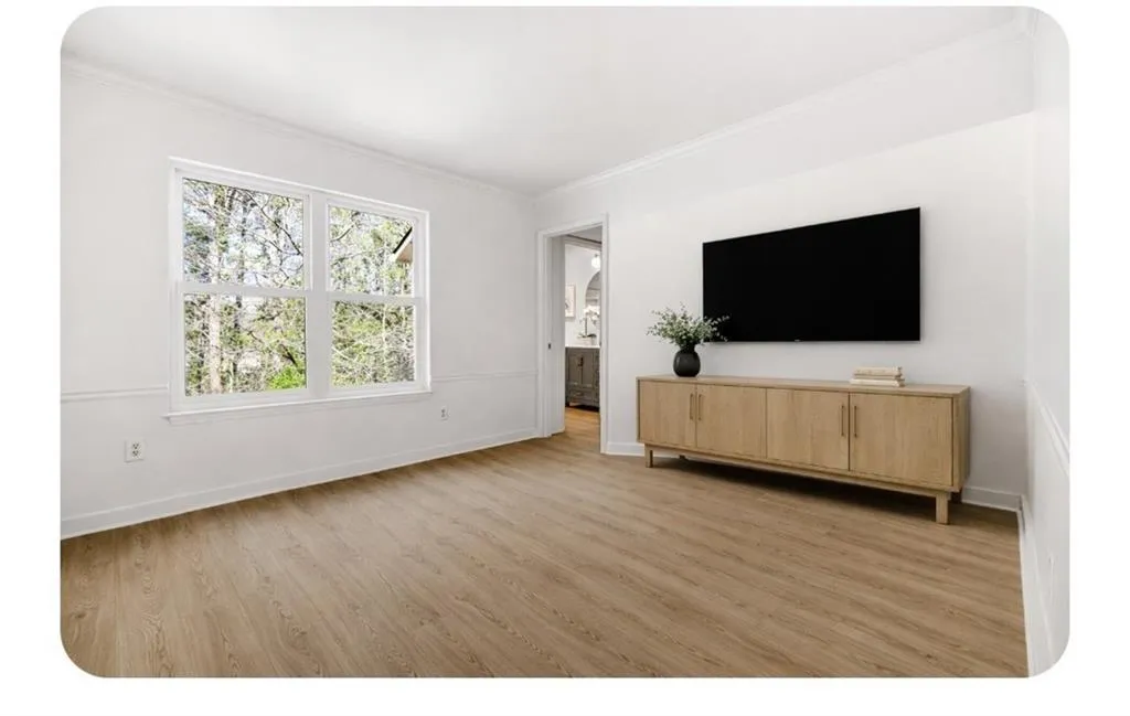 Living area featuring arched walkways, light wood-style floors, and ornamental molding