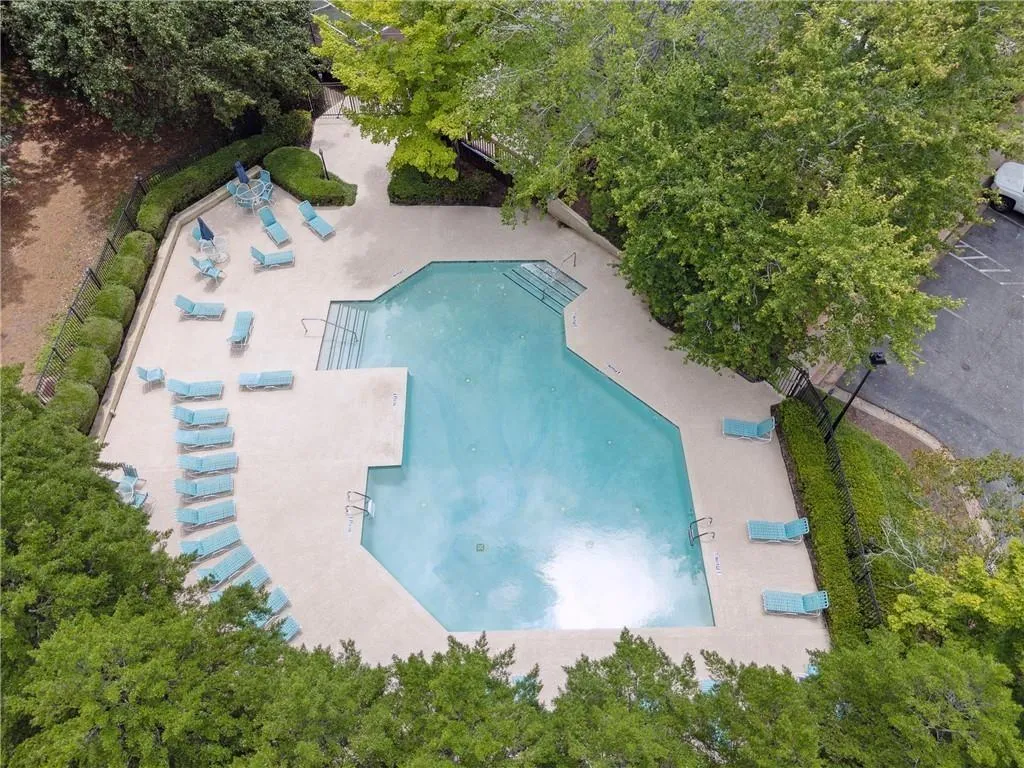 Community pool with a patio area and view of wooded area
