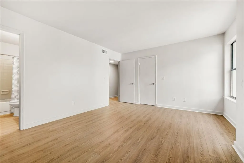 Unfurnished bedroom featuring light wood-style floors and ensuite bathroom