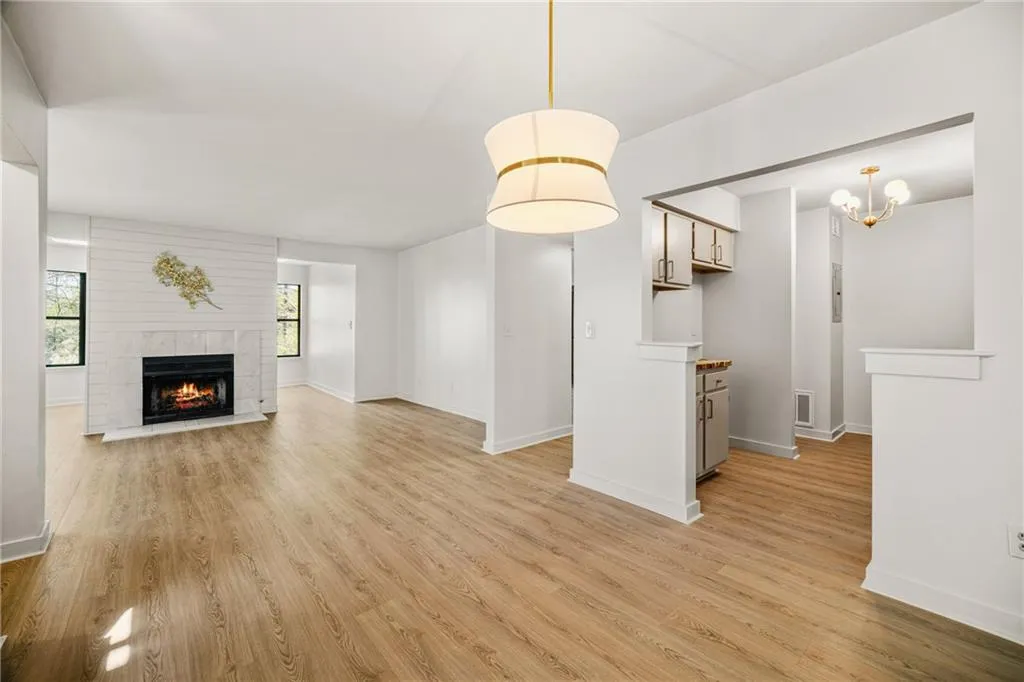 Unfurnished living room with light wood finished floors, a tile fireplace, and hanging lights