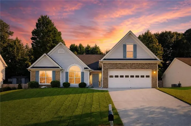 Traditional-style residence featuring a combination of siding and brick veneer, an arched window, a two-car garage, and a concrete driveway