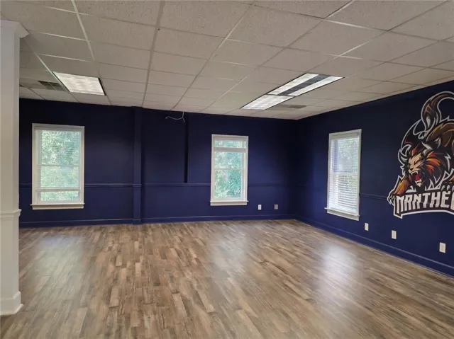Expansive room featuring wood-finish flooring, multiple windows with blinds, and recessed lighting