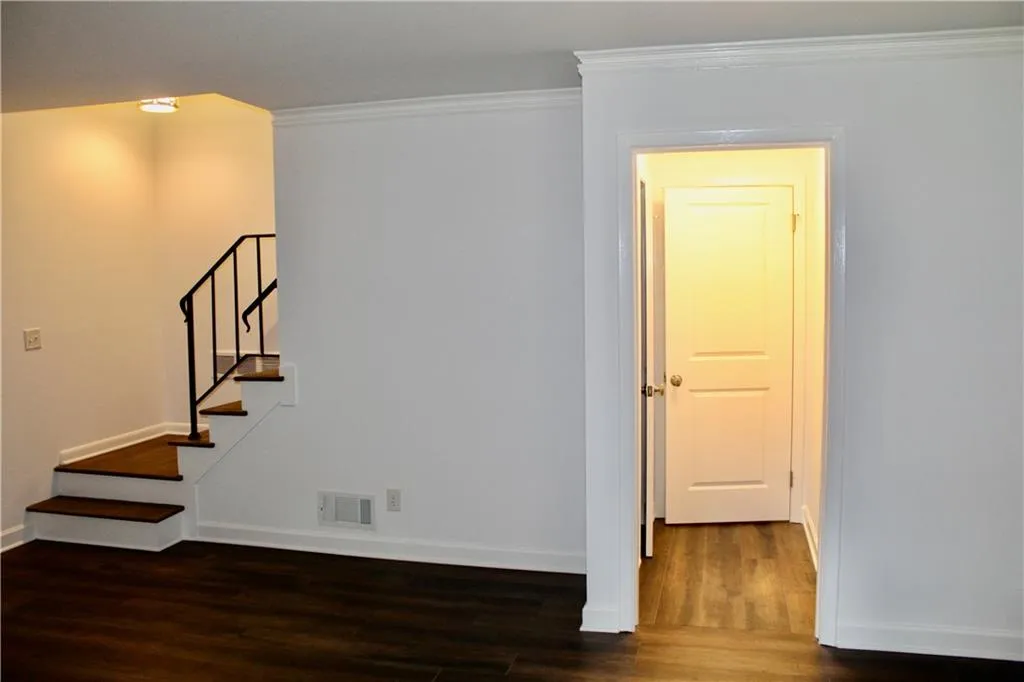 Empty room with wood finished floors, ornamental molding, and stairs