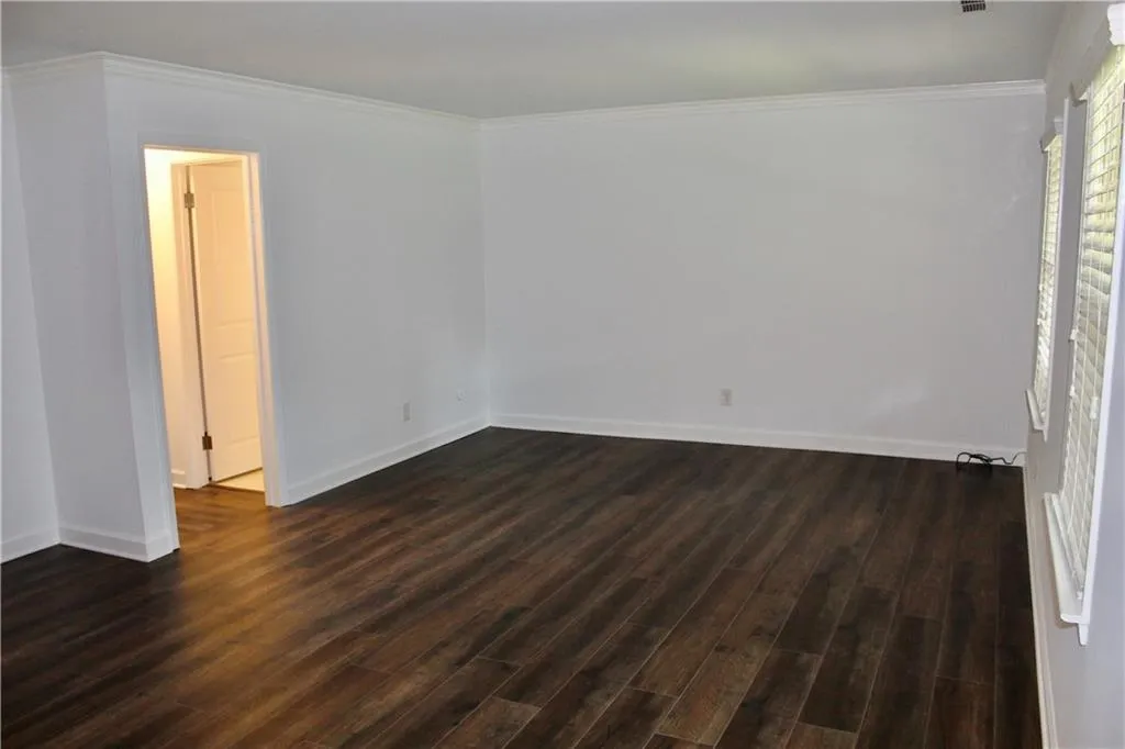 Unfurnished room featuring dark wood-style floors and crown molding