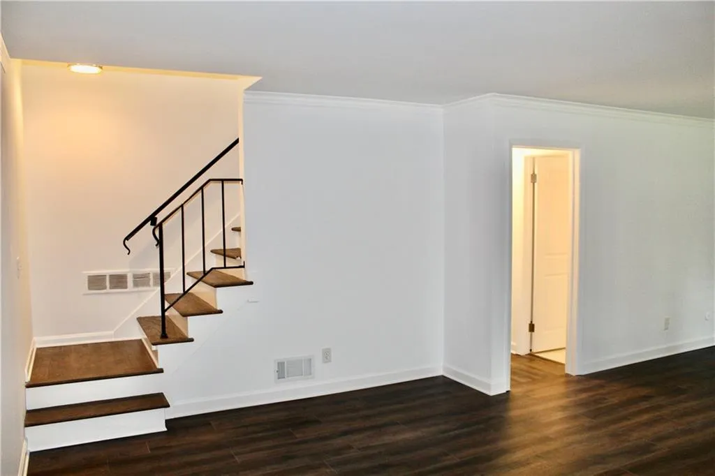 Staircase with wood finished floors and crown molding