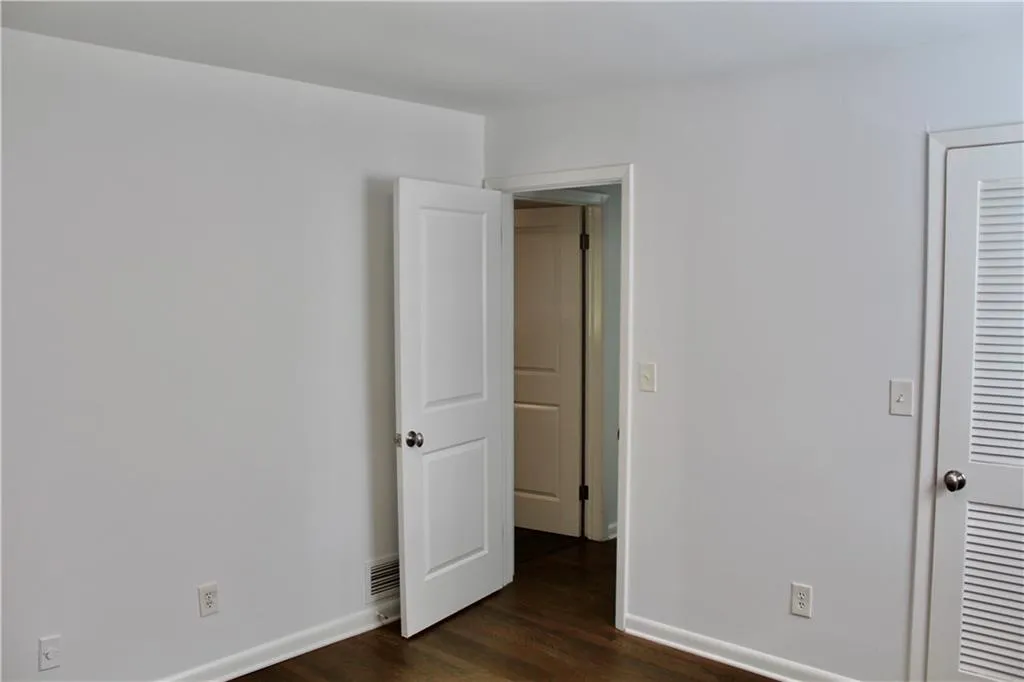 Unfurnished bedroom featuring dark wood-type flooring and baseboards