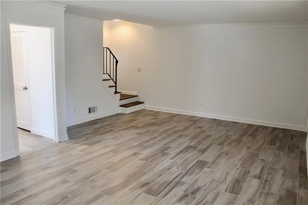 Spare room featuring light wood-style floors, stairs, and crown molding
