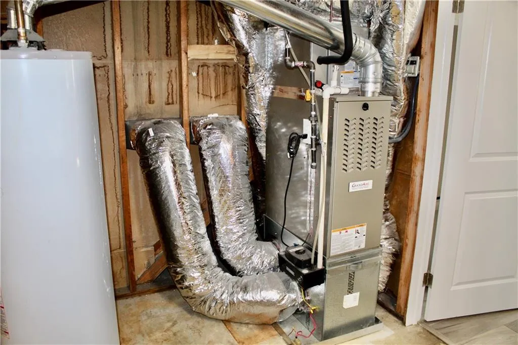 Utility room featuring water heater and heating unit