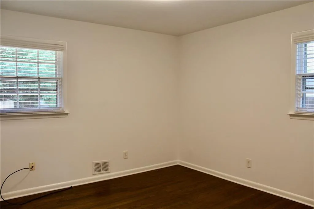 Empty room with dark wood-type flooring and healthy amount of natural light