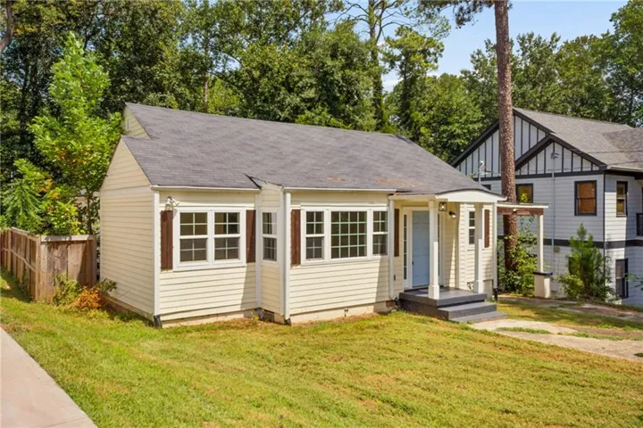 Single-story residence featuring light-colored siding, a covered front entry, and multiple windows with decorative shutters