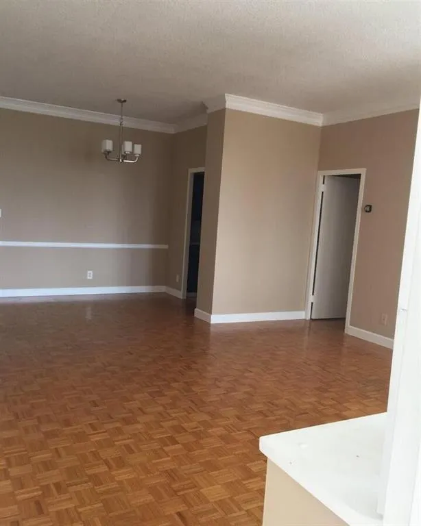 Spare room with ornamental molding, a chandelier, and a textured ceiling