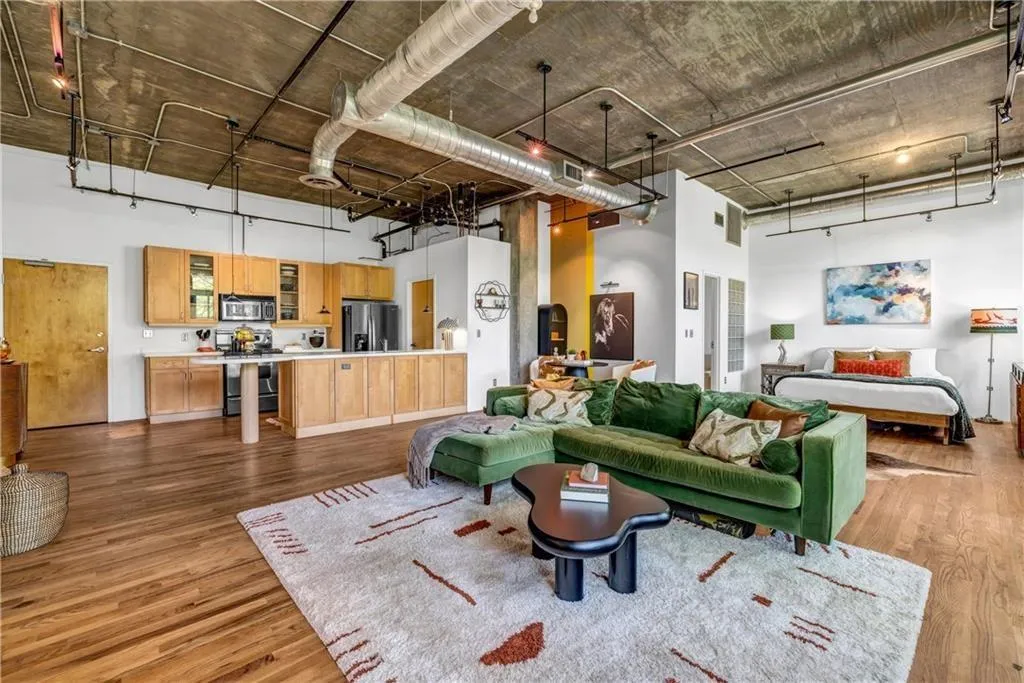 Living area with a towering ceiling, wood finished floors, and track lighting
