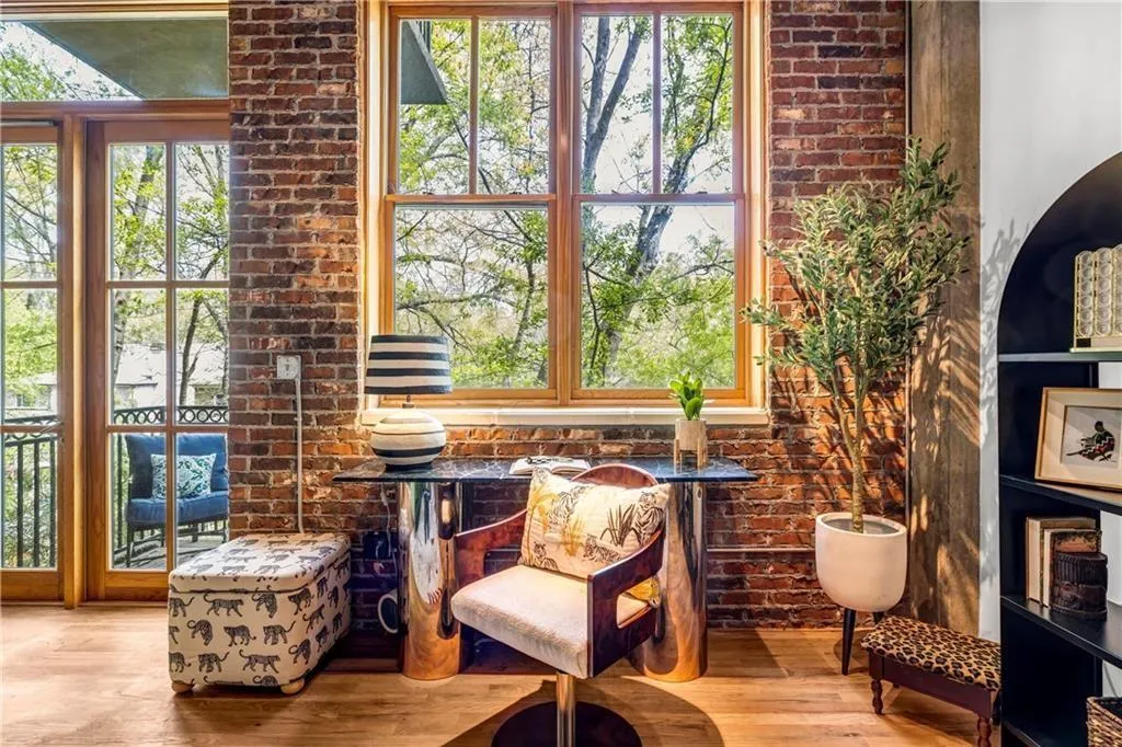 Office area featuring wood finished floors, healthy amount of natural light, and brick wall