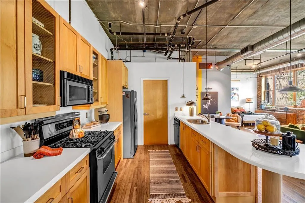 Kitchen with stainless steel appliances, a sink, dark wood-type flooring, light countertops, and glass insert cabinets