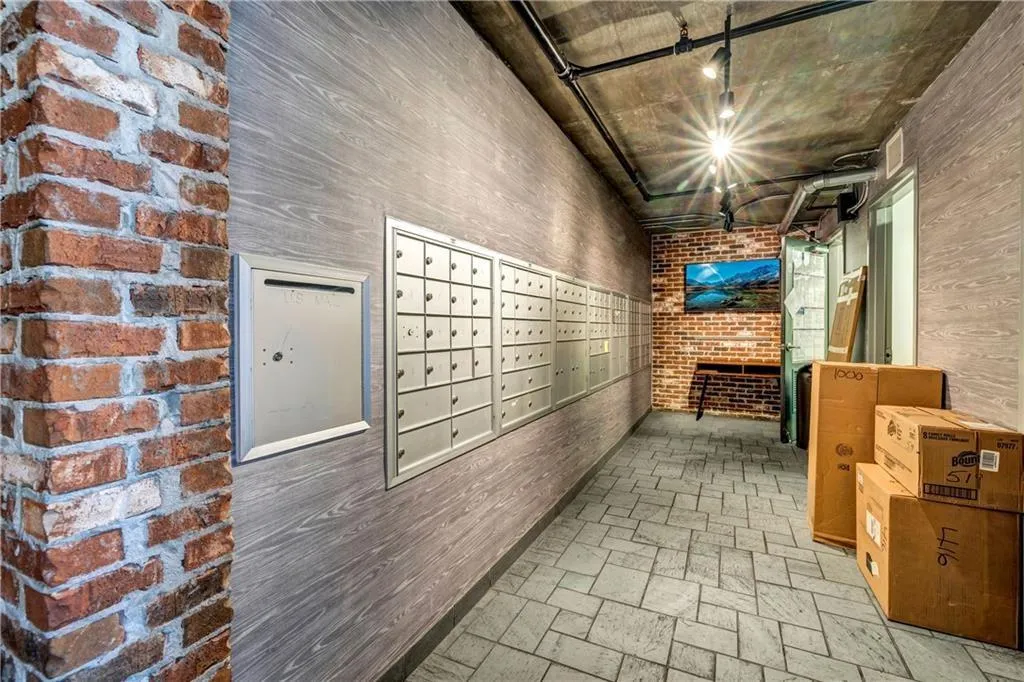 Hall with mail area, track lighting, brick wall, and brick patterned flooring