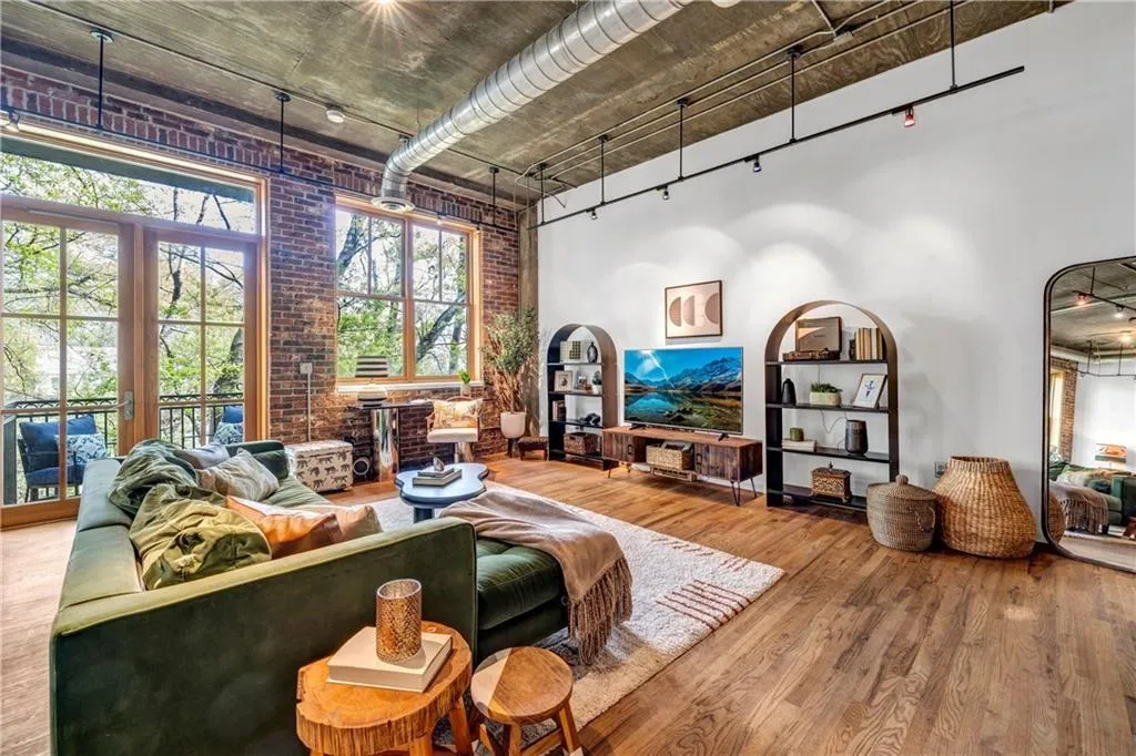 Living room featuring wood finished floors, a high ceiling, and brick wall